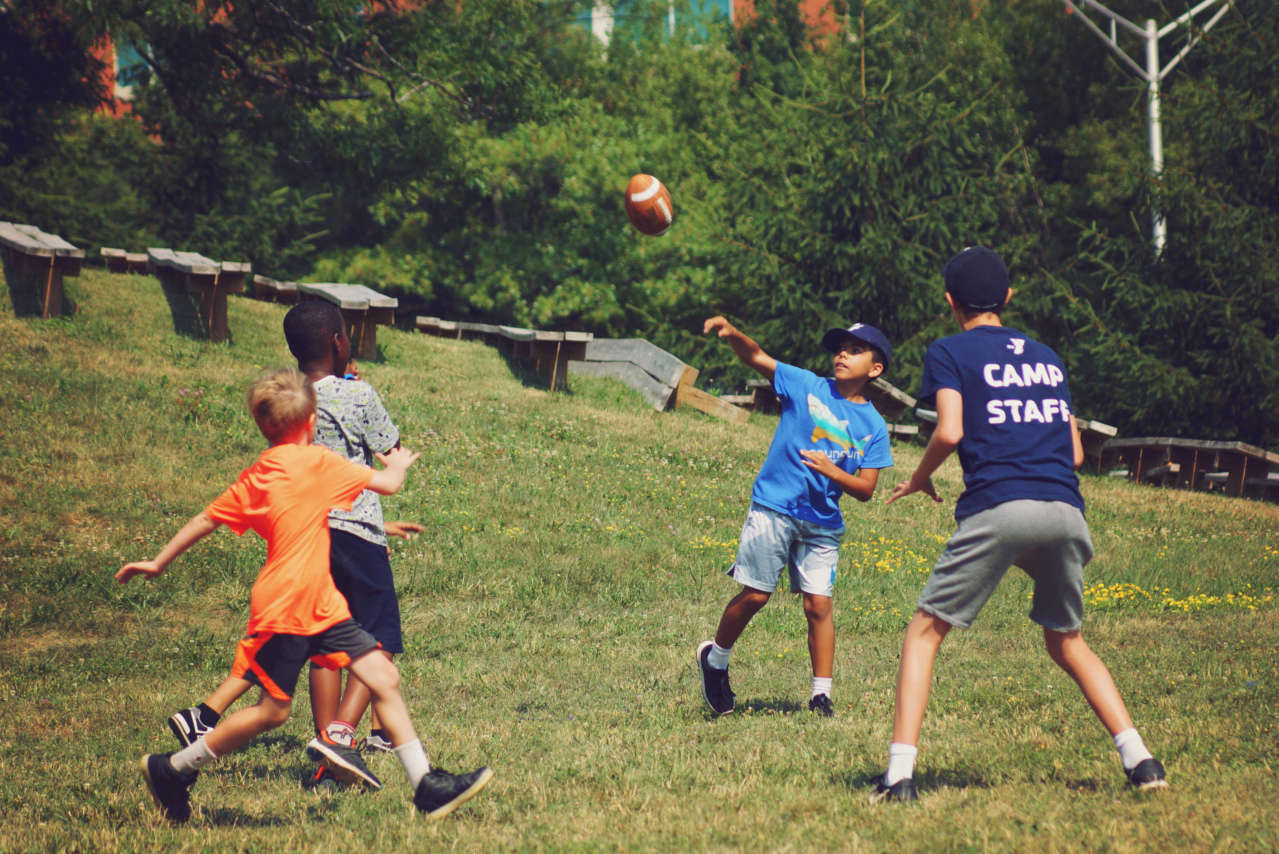 A group of kids playing football during summer near Indian Lake in Worcester, MA