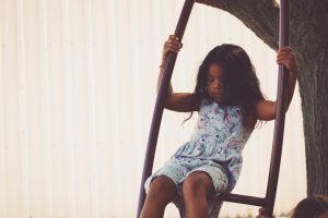 A young girl swings joyfully on a swing at a summer camp in Central Massachusetts.