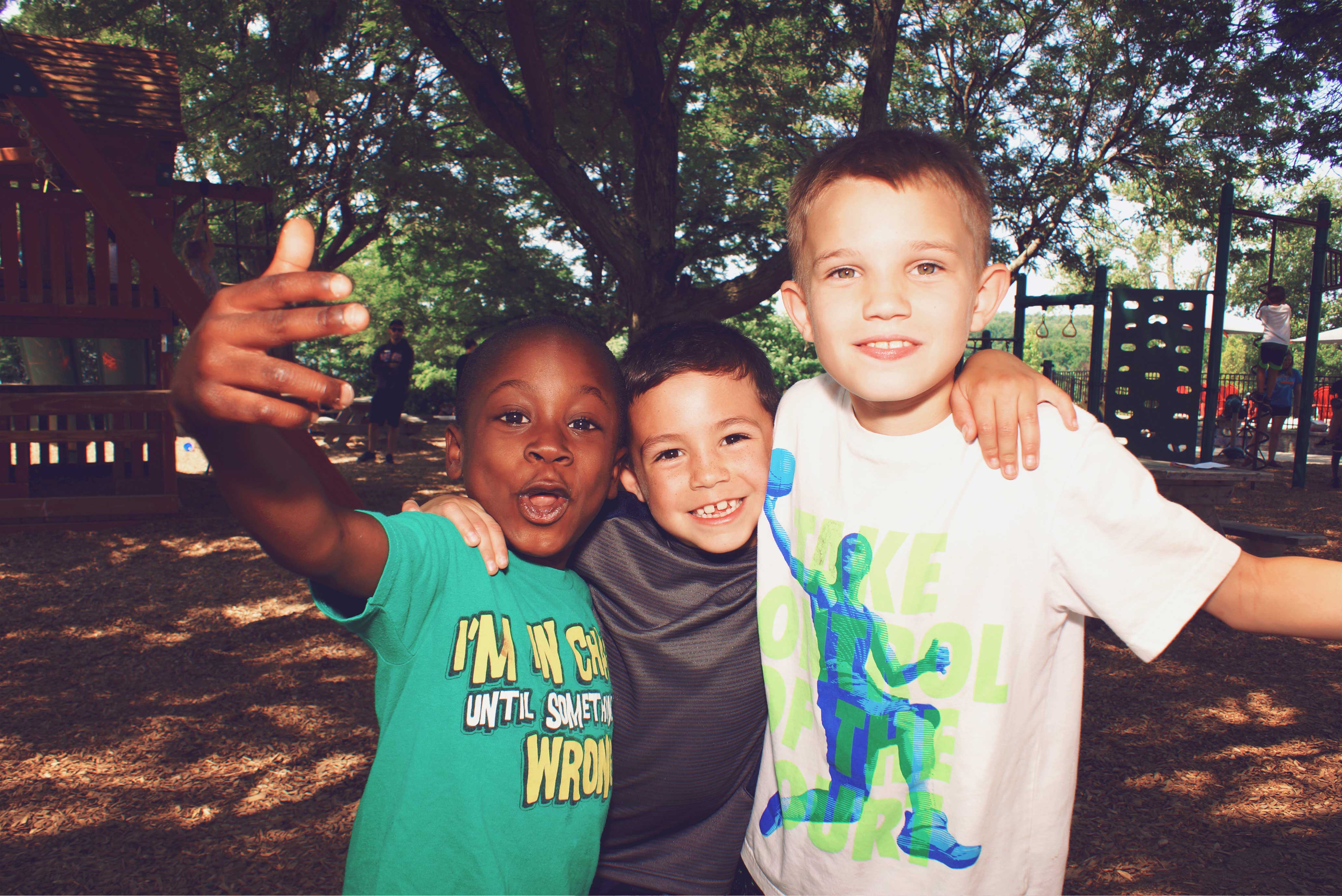 Three young boys posing for a picture at a summer camp in Central Massachusetts