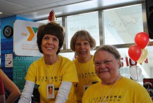 Three smiling women in yellow t-shirts at the LIVESTRONG event in Central Massachusetts.