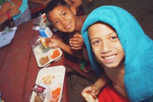 Two boys smiling while enjoying lunch together in summer camp in Central Massachusetts.