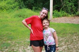 Two girls standing together, enjoying their time at summer camp in Central Massachusetts.