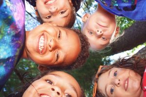 Children at YMCA Camp Lowe in Central Massachusetts smiling and looking up at the camera