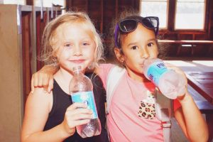 Two young girls at YMCA Camp Lowe in Central Massachusetts drink water from plastic bottles