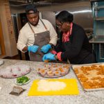 Staff preparing trays of food in the YMCA of Central Massachusetts kitchen