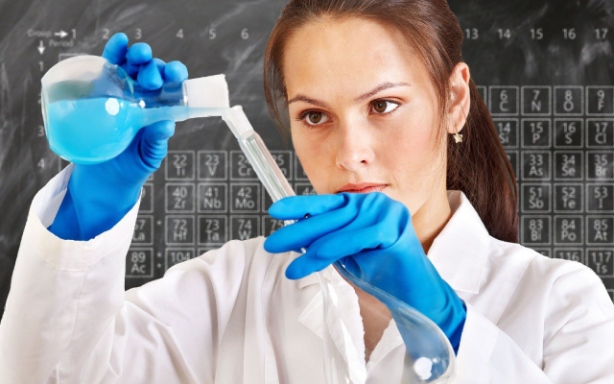 A scientist in a lab coat and blue gloves is experimenting with blue liquid