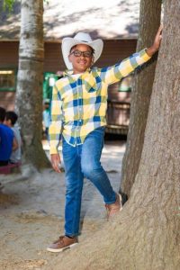 A boy wearing a white cowboy hat is attending a summer camp in Central Massachusetts