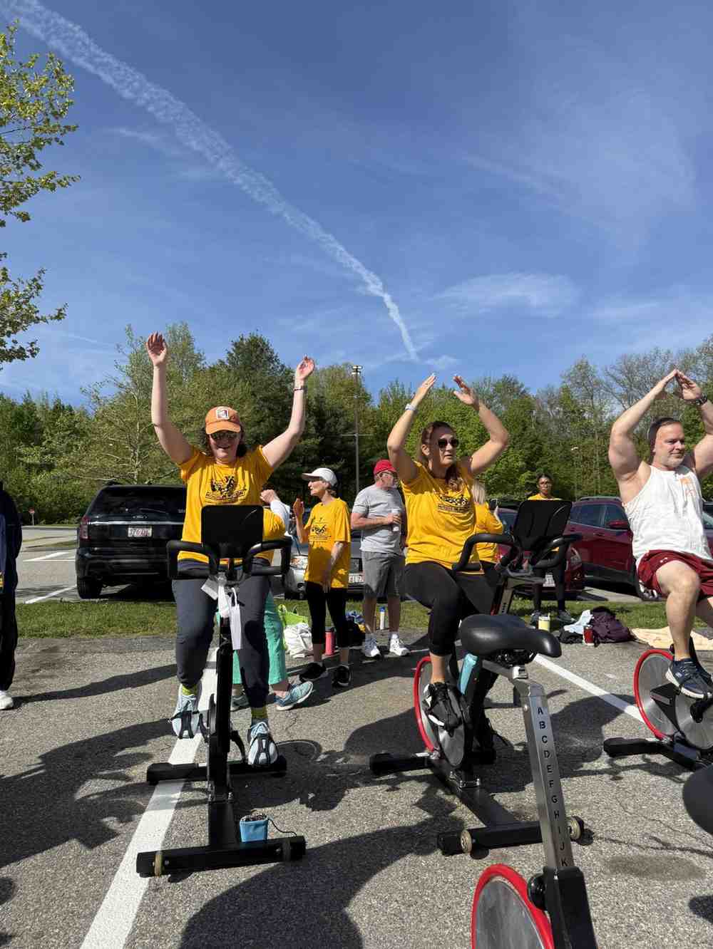 YMCA Mission in Motion participants raising hands on stationary bikes during an outdoor event